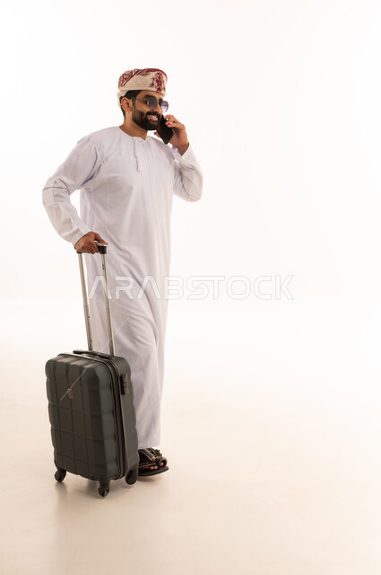 رجل عماني مع حقيبة سفر يتحدث بالهاتف