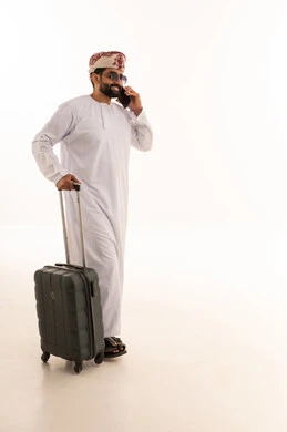 رجل عماني مع حقيبة سفر يتحدث بالهاتف