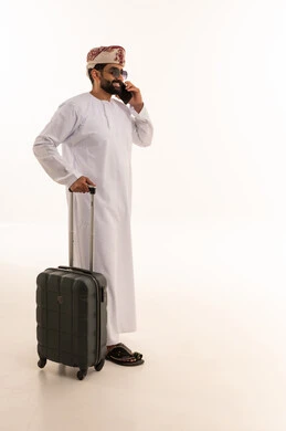 Omani Man with Suitcase Talking on Smartphone