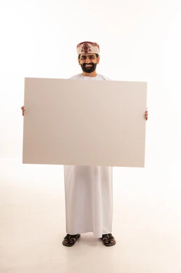 رجل عُماني يحمل لوحة بيضاء فارغة في الاستوديو