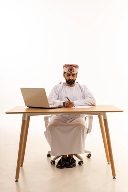 Omani Man Working at Office Desk with Laptop