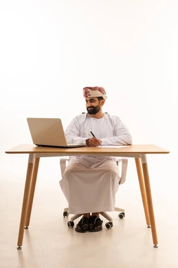 Omani Man in Traditional Dress Working on Laptop