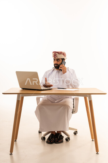رجل أعمال عُماني يعمل بالحاسوب والهاتف المحمول