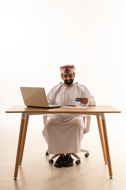 رجل عماني يستخدم بطاقة ائتمان وكمبيوتر محمول