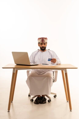 رجل عماني مع كمبيوتر محمول وبطاقة ائتمان