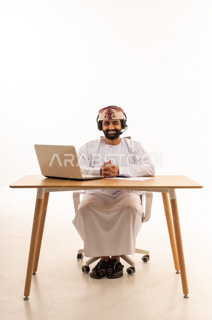 رجل عُماني مع كمبيوتر وسماعة في المكتب