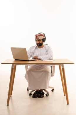 رجل عُماني يعمل على كمبيوتر محمول بسماعة رأس
