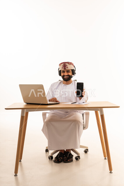 Omani Man at Office Desk with Headset and Phone