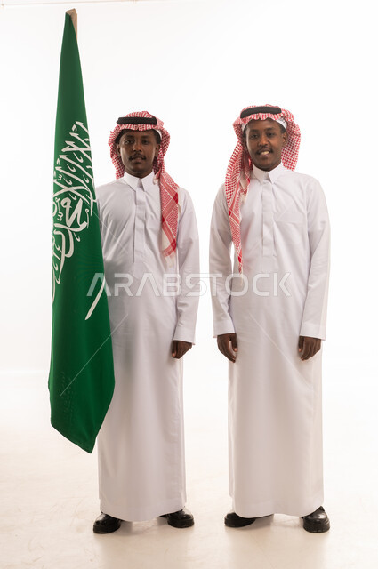 رجلان سعوديان يحملان علم السعودية بالزي الرسمي