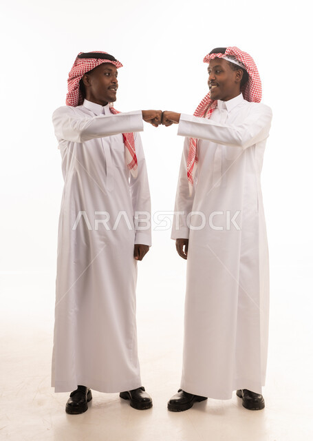 رجلان سعوديان بالزي التقليدي يضربان قبضتيهما