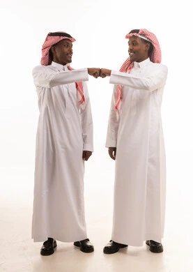 رجلان سعوديان بالزي التقليدي يضربان قبضتيهما