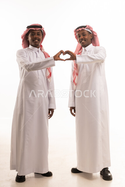 رجلان سعوديان بالثوب التقليدي يشكلان علامة القلب باليد