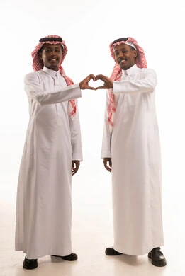رجلان سعوديان بالثوب التقليدي يشكلان علامة القلب باليد