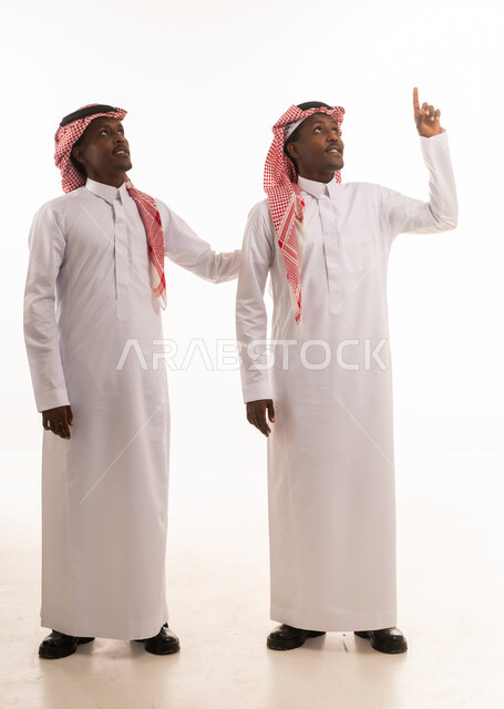 رجلان بالزي السعودي يشيران للأعلى بخلفية بيضاء