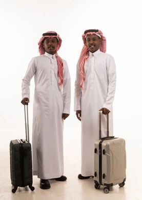 رجلان سعوديان مع حقائب سفر على خلفية بيضاء