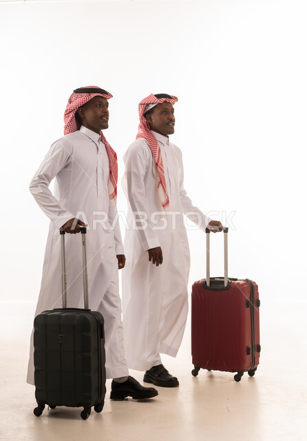 رجال سعوديون بالزي التقليدي مع حقائب سفر