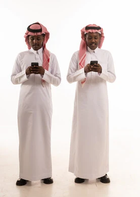 رجال سعوديون بالثوب التقليدي يستخدمون الهواتف الذكية