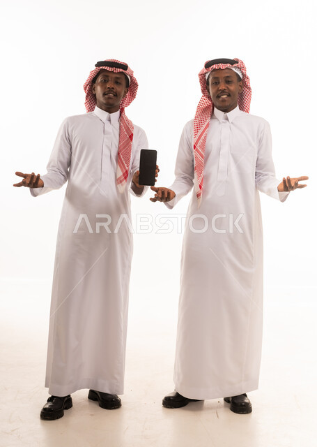 رجال سعوديون بالزي التقليدي يحملون هاتف ذكي
