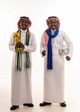 رجال سعوديون بالزي التقليدي يحملون كأس كرة القدم