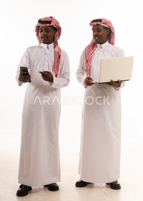 رجال سعوديون يستخدمون لابتوب وهاتف ذكي بخلفية بيضاء