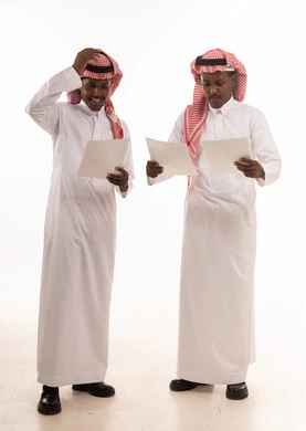 Two Saudi Men Reading Documents in Traditional Thobes
