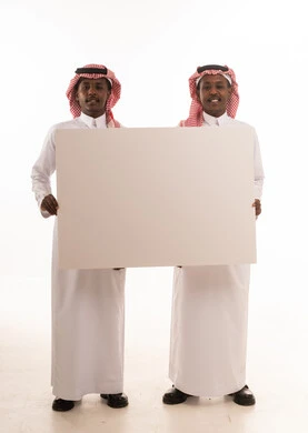 رجلان سعوديان يحملان لوحة بيضاء فارغة في استوديو