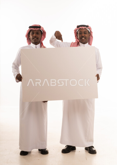 رجلان سعوديان بالزي التقليدي يحملان لوحة بيضاء فارغة