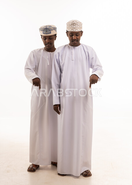 Two Omani Men in Traditional Dishdasha Pointing Down