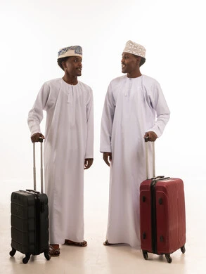 رجال عمانيون مع حقائب سفر بالزي العماني التقليدي