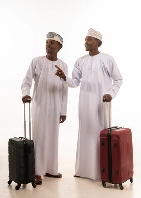 رجال عمانيون بالزي التقليدي مع حقائب سفر