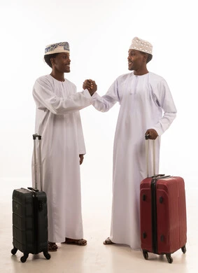 رجال عمانيون مع حقائب سفر يتصافحان على خلفية بيضاء