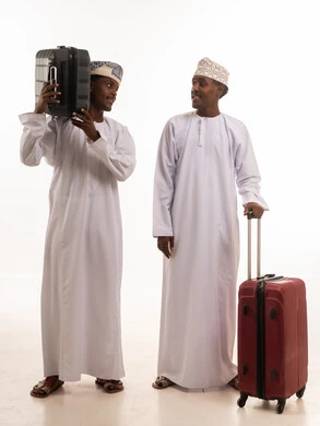 رجال عمانيون بالزي التقليدي مع حقائب سفر