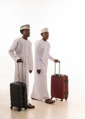 Omani Men in Traditional Dress Walking with Luggage