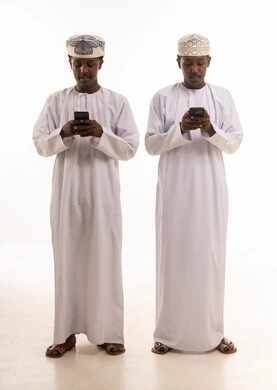 رجال عمانيون بالزي التقليدي يستخدمون الهواتف الذكية