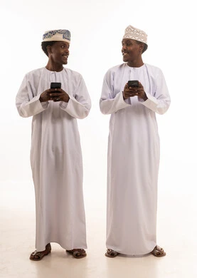 رجال عمانيون بالزي التقليدي يستخدمون الهواتف الذكية