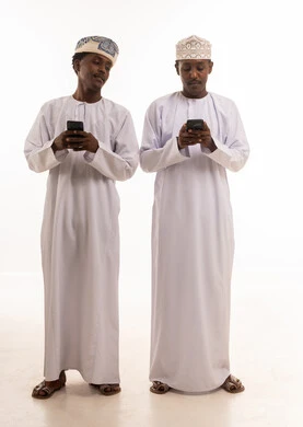 رجال عمانيون بالزي التقليدي يستخدمون الهواتف الذكية