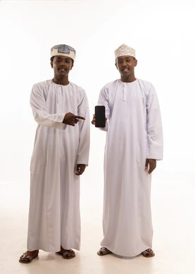 رجال عمانيون بالزي التقليدي يشيرون إلى هاتف ذكي