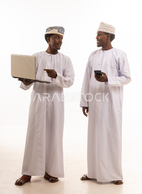 رجال عمانيون يستخدمون اللابتوب والهاتف في استوديو