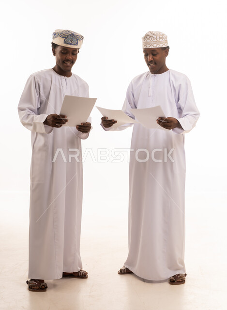 رجال عمانيون بالزي التقليدي يحملون أوراقاً رسمية