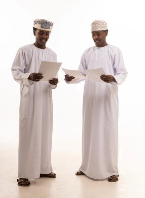 Omani Men in Traditional Attire Holding Documents