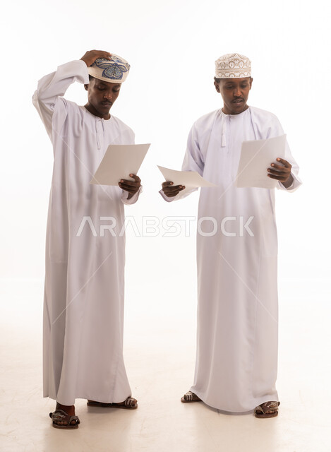 Omani Men in Traditional Dress Reviewing Documents