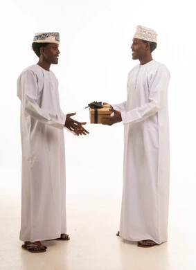 رجال عمانيون بالزي التقليدي يتبادلون صندوق هدايا