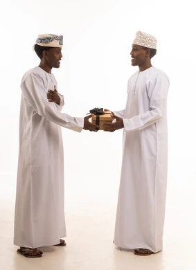 Omani Men in Traditional Dishdasha Exchanging a Gift