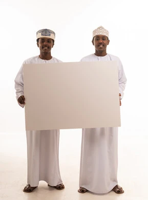 رجال عمانيون بالزي التقليدي يحملون لوحة بيضاء فارغة