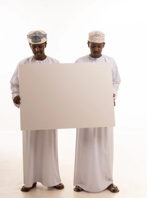 رجال عمانيون يحملون لوحة بيضاء فارغة في استوديو