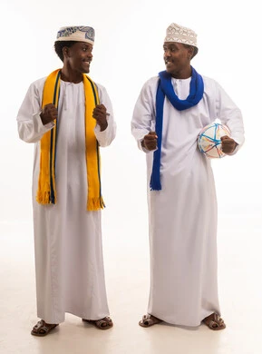 رجال عمانيون بالزي التقليدي يشجعون كرة القدم