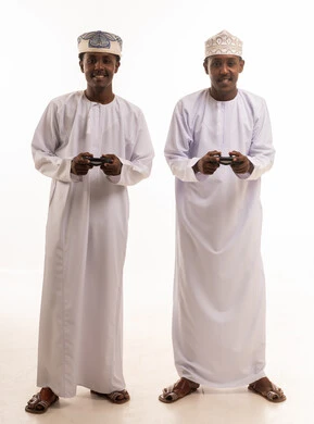 رجال عمانيون بالزي التقليدي يلعبون ألعاب الفيديو