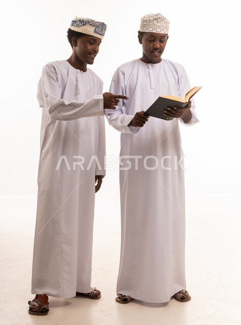 رجال عمانيون يقرؤون كتاباً بالزي التقليدي