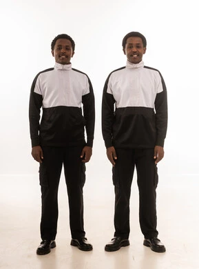 رجلان عمانيان بزي عمل موحد يقفان أمام خلفية بيضاء