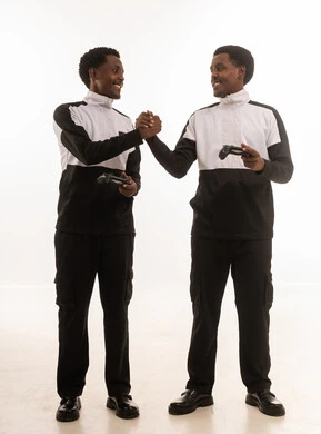 رجال عمانيون يحملون أجهزة تحكم ألعاب ويتصافحون